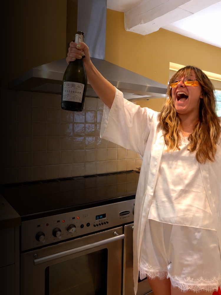 Woman celebrating with champagne in a kitchen